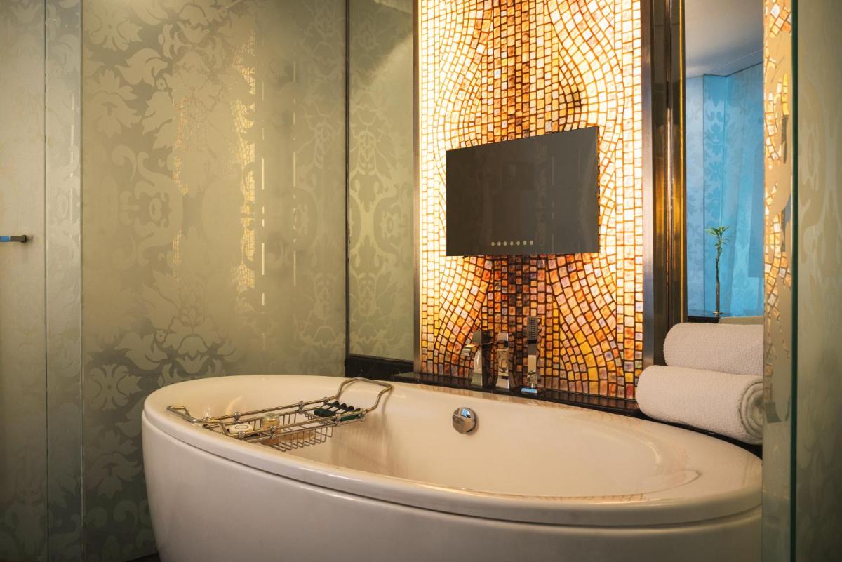 a bath tub in a bathroom with a television on the wall at Sofitel Mumbai BKC in Mumbai