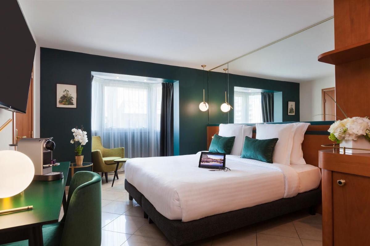 une chambre d'hôtel avec un lit et un bureau avec un ordinateur portable dessus dans l'établissement Nehô Suites Cannes Croisette, à Cannes