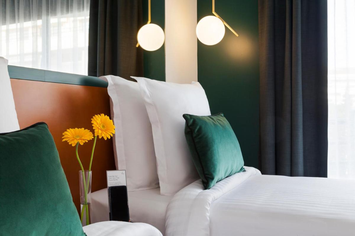 une chambre avec un lit blanc avec des oreillers verts et jaunes dans l'établissement Nehô Suites Cannes Croisette, à Cannes