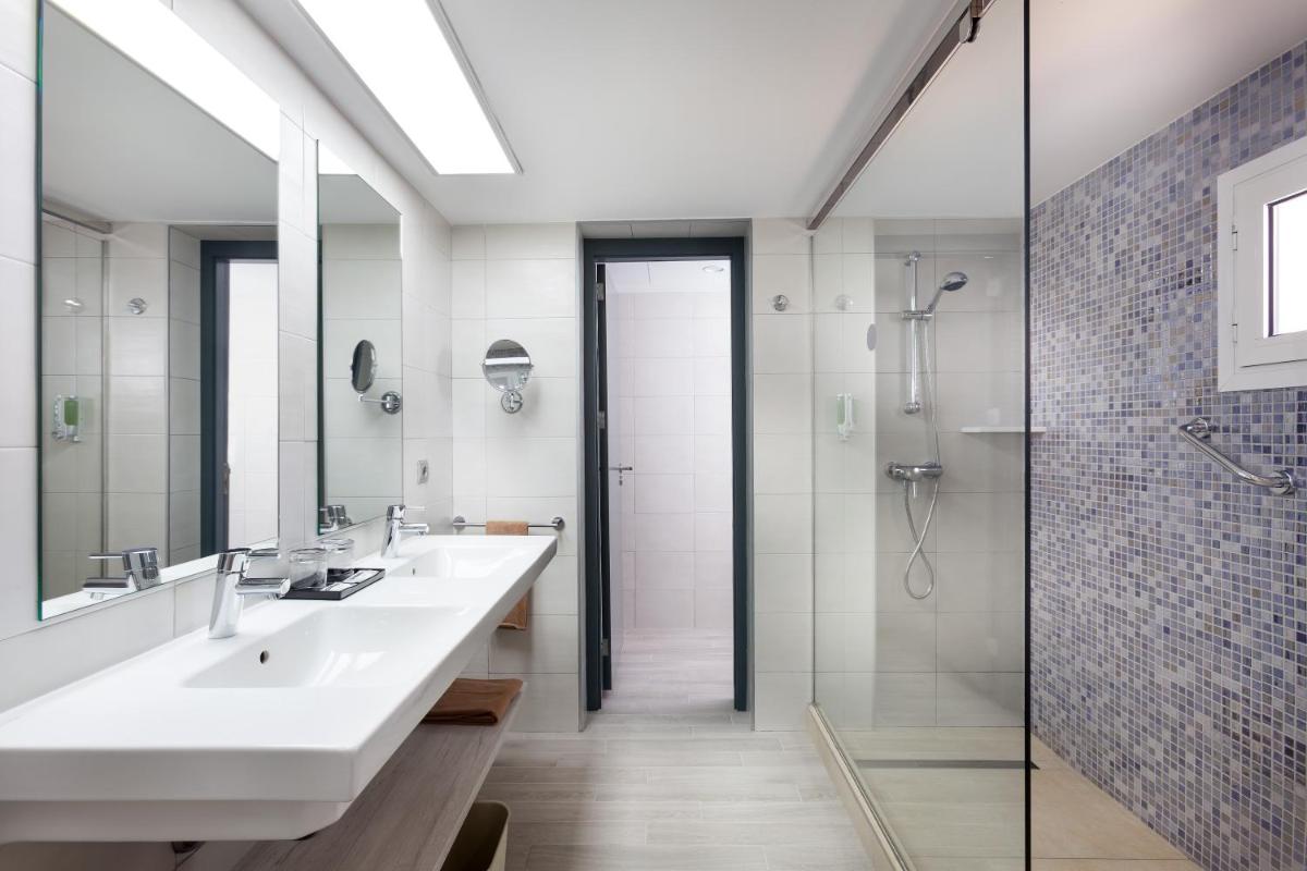 Un baño con dos lavabos y una ducha. en Hotel Riu Chiclana - All Inclusive, en Chiclana de la Frontera