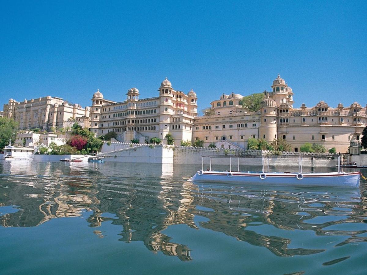 a large building with a blue boat in the water at Shiv Niwas Palace by HRH Group of Hotels in Udaipur