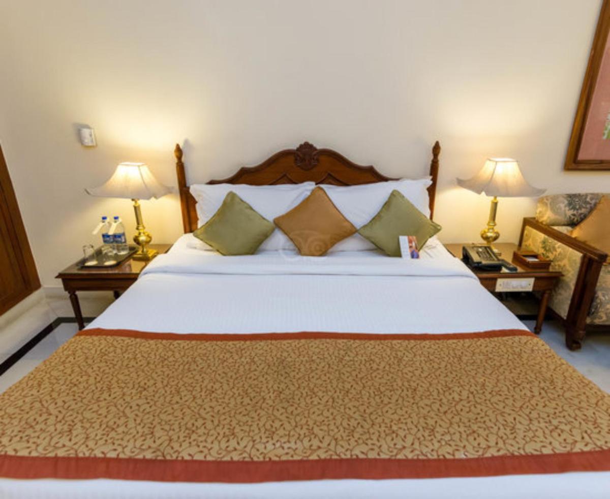 a bedroom with a large white bed with two lamps at Shiv Niwas Palace by HRH Group of Hotels in Udaipur
