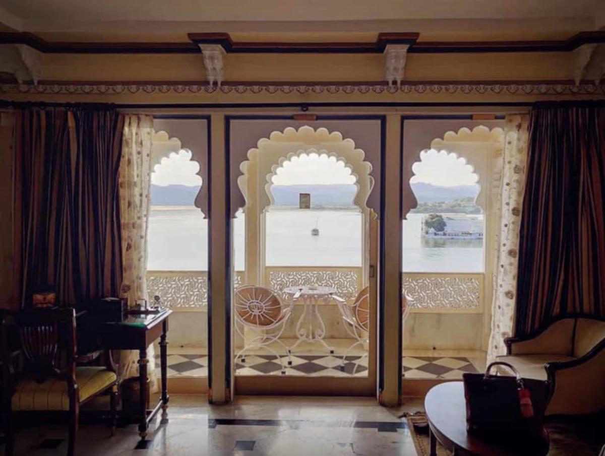 a room with glass doors with a view of a table at Shiv Niwas Palace by HRH Group of Hotels in Udaipur