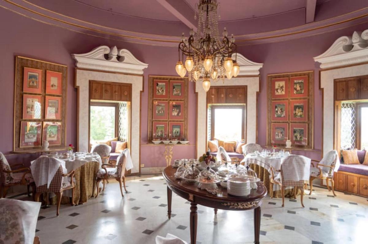 a dining room with a table and a chandelier at Shiv Niwas Palace by HRH Group of Hotels in Udaipur