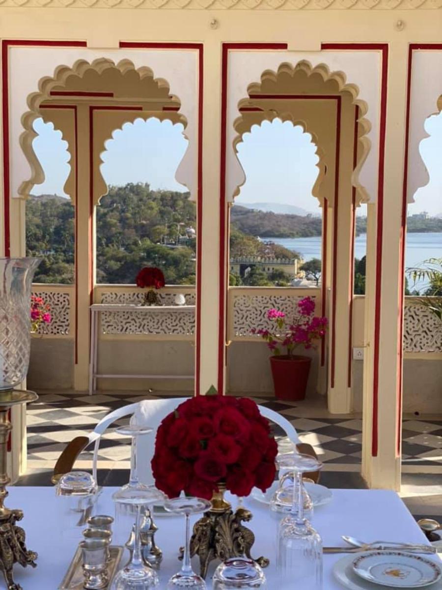 a table with a vase of red flowers on a table at Shiv Niwas Palace by HRH Group of Hotels in Udaipur