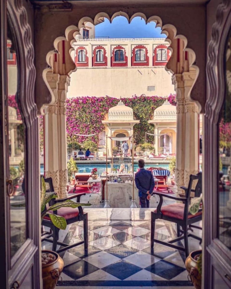 a man standing at a table in front of a building at Shiv Niwas Palace by HRH Group of Hotels in Udaipur