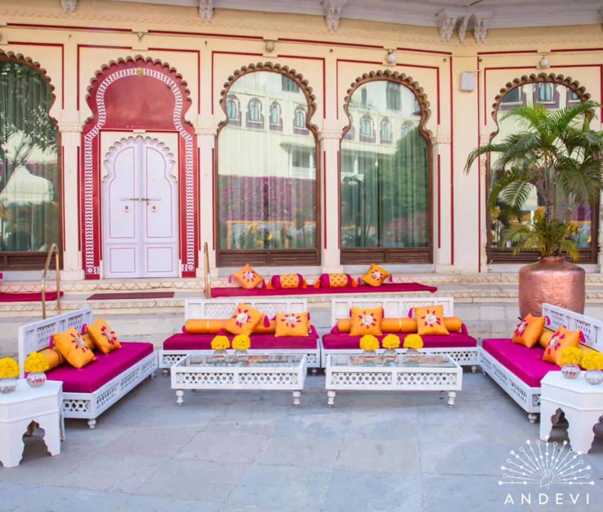 a row of benches with orange pillows in front of a building at Shiv Niwas Palace by HRH Group of Hotels in Udaipur
