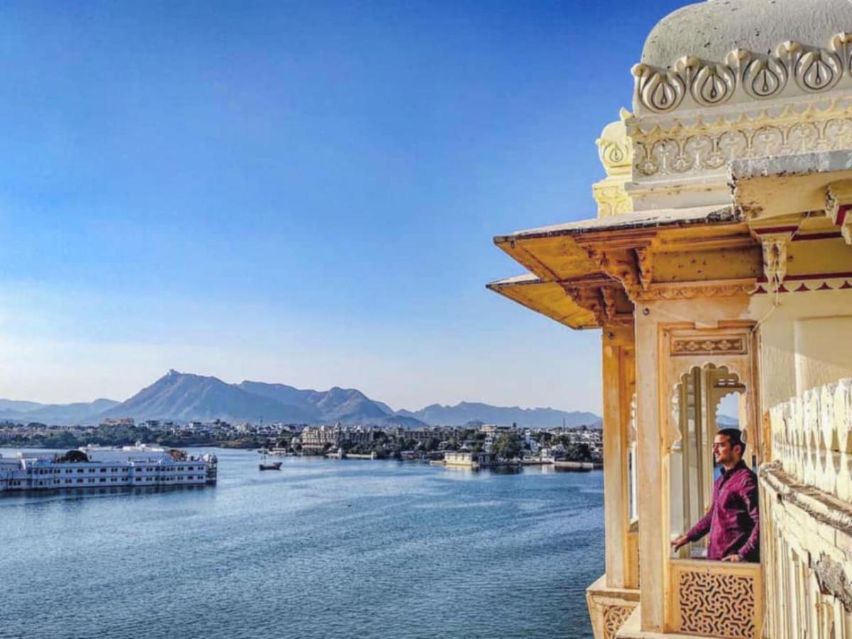 a man sitting on a balcony looking out over the water at Shiv Niwas Palace by HRH Group of Hotels in Udaipur