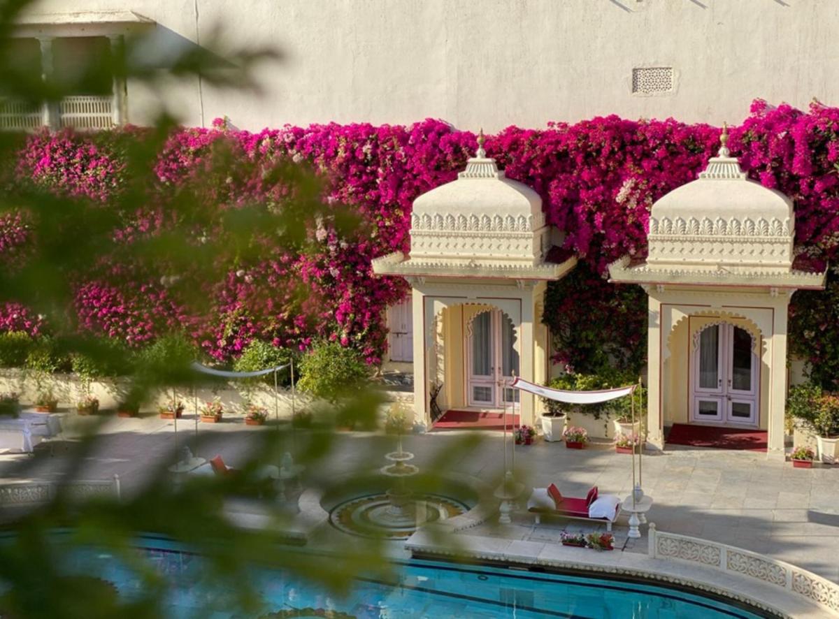 a building with a swimming pool and pink flowers at Shiv Niwas Palace by HRH Group of Hotels in Udaipur