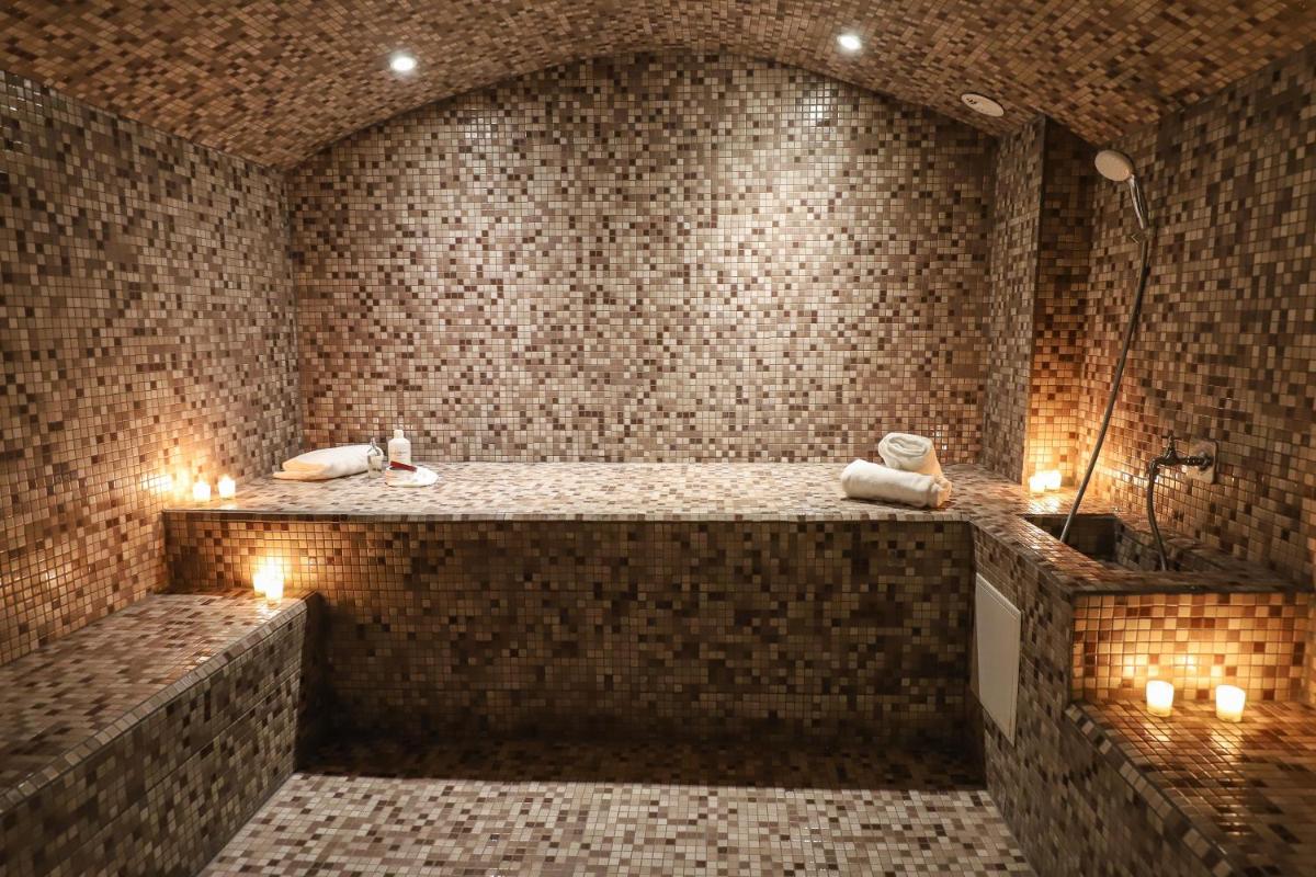 une salle de bains avec une grande baignoire éclairée aux bougies dans l'établissement Le Miel des Muses, à Brive-la-Gaillarde