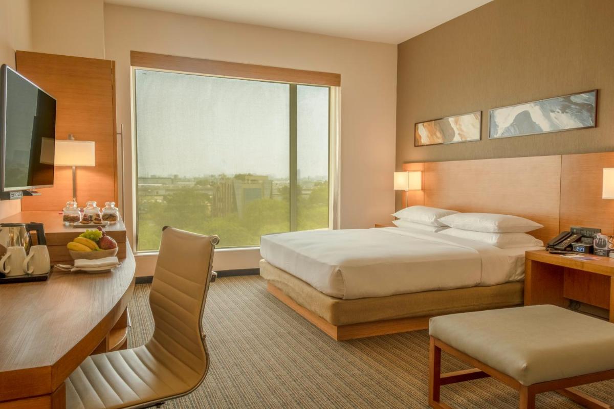 a hotel room with a bed and a desk and a window at Hyatt Place Gurgaon Udyog Vihar in Gurgaon