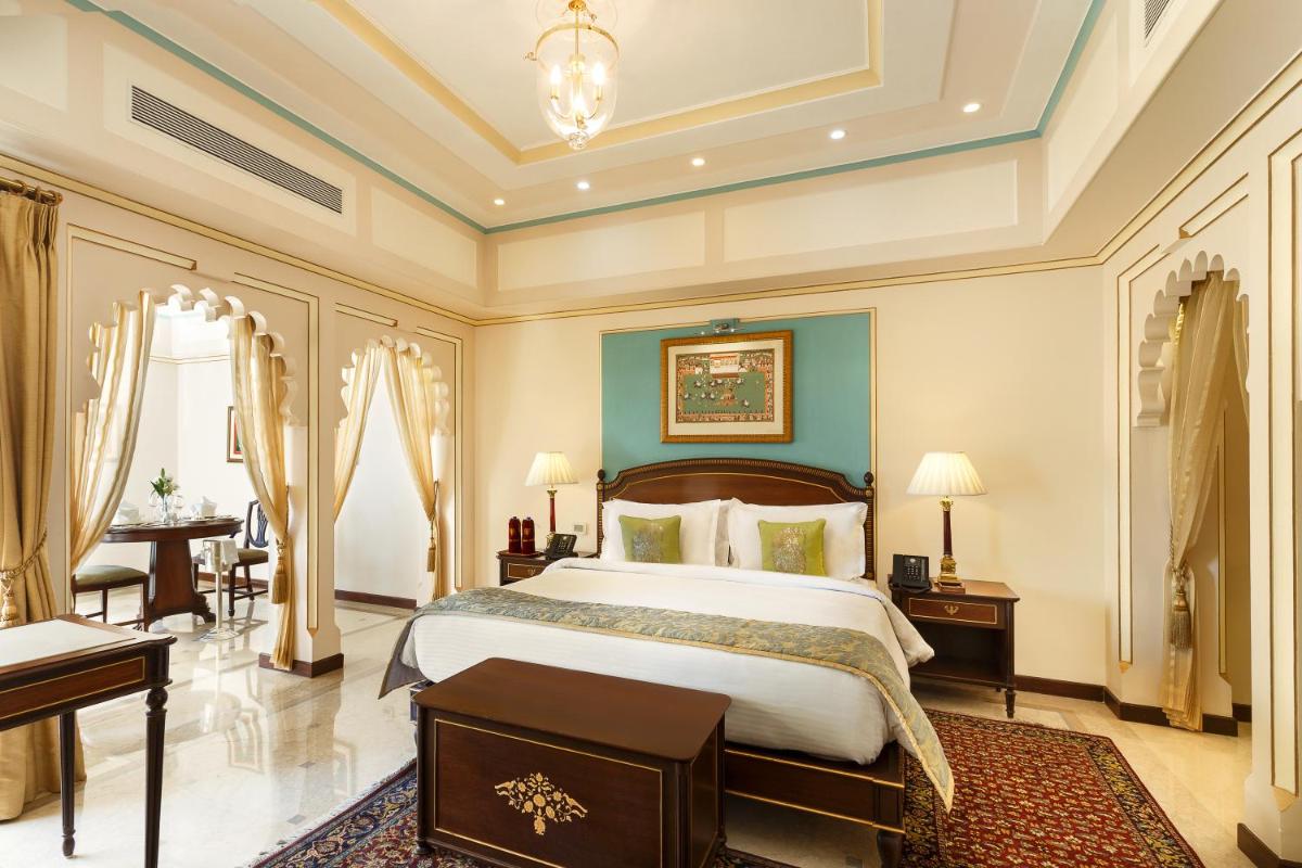a bedroom with a large bed and a desk at Taj Fateh Prakash Palace Udaipur in Udaipur