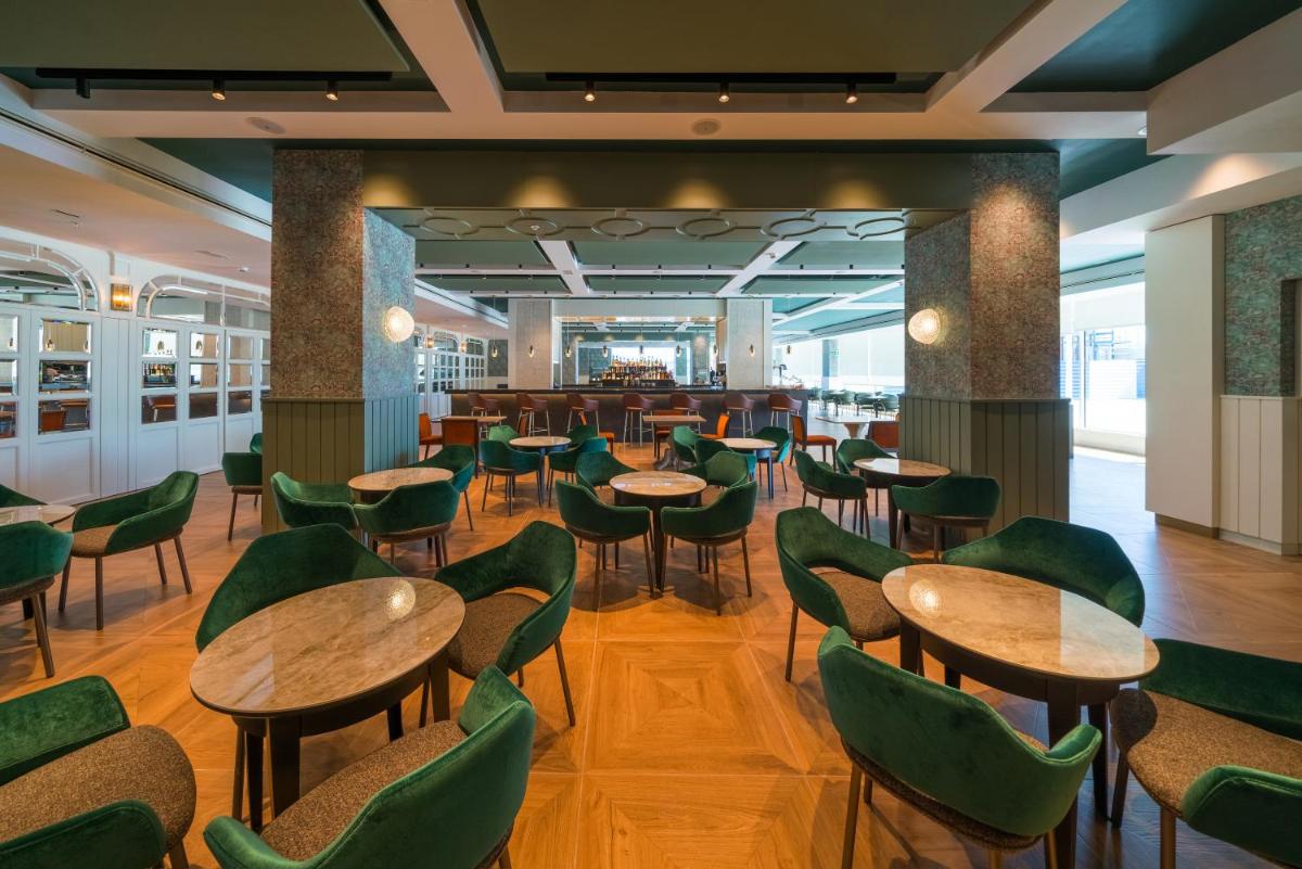 Un restaurante con mesas de madera y sillas verdes. en Catalonia Donosti, en San Sebastián