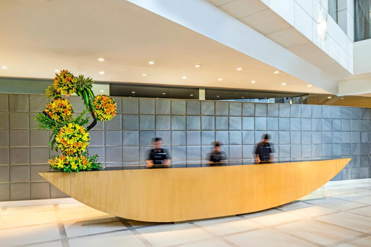 a lobby with a reception desk with people in the background at The Park Chennai in Chennai a lobby with a reception desk with people in the background at The Park Chennai in Chennai