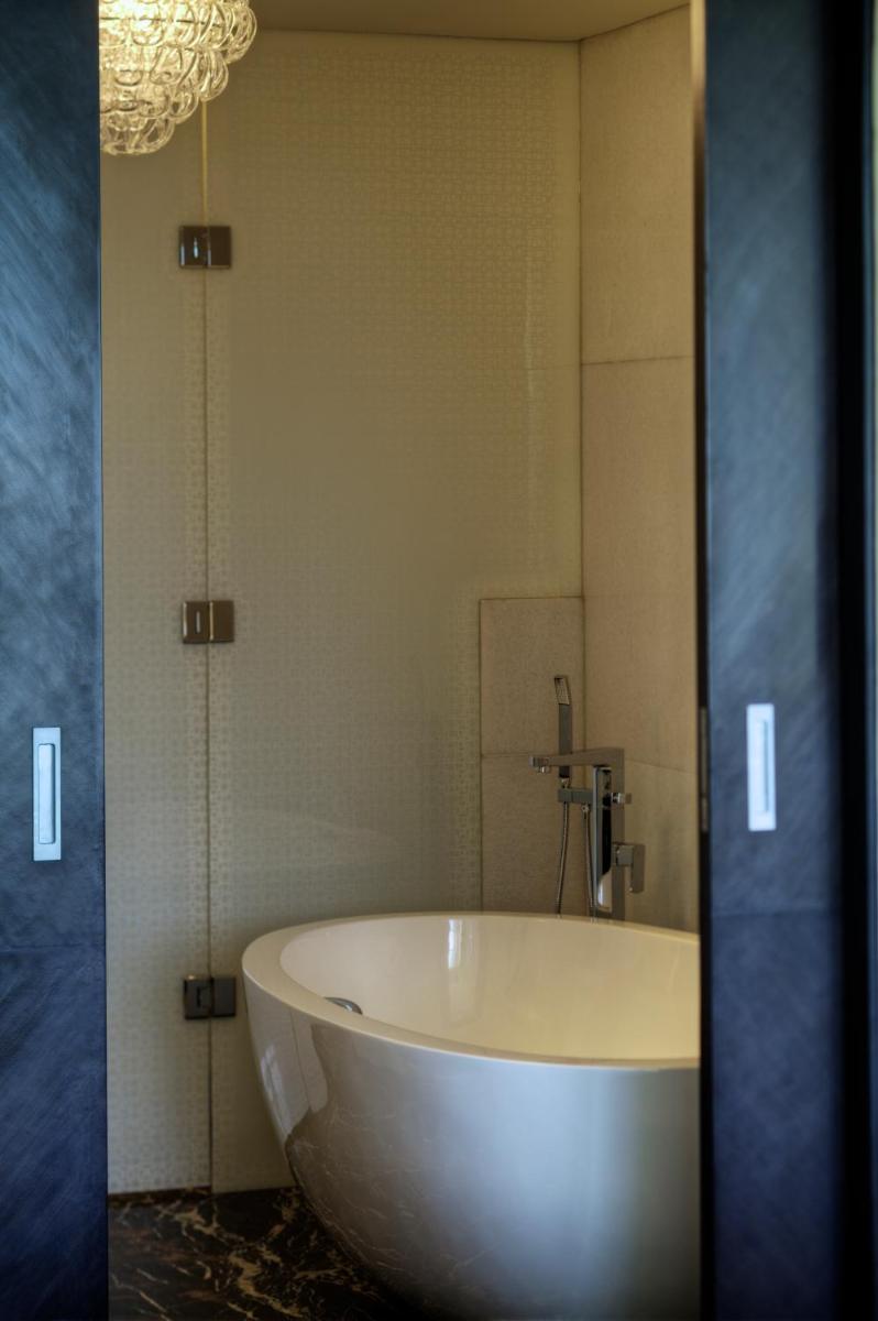 a white tub in a bathroom with a mirror at Park Hyatt Hotel and Residences, Hyderabad in Hyderabad