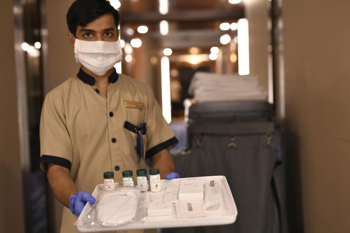 a man in a mask holding a tray with medicines at Radisson Blu Plaza Delhi Airport in New Delhi a man in a mask holding a tray with medicines at Radisson Blu Plaza Delhi Airport in New Delhi