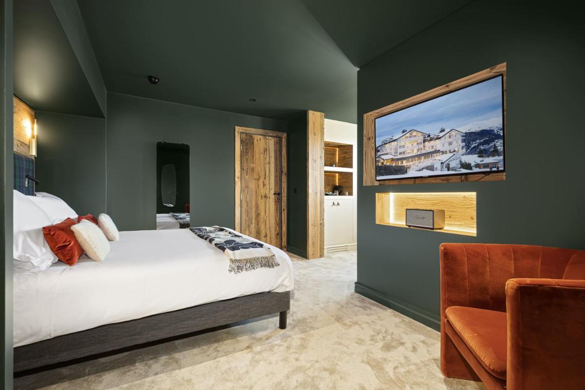 une chambre avec un lit et une télévision au mur dans l'établissement Hotel Le Chabichou, à Courchevel