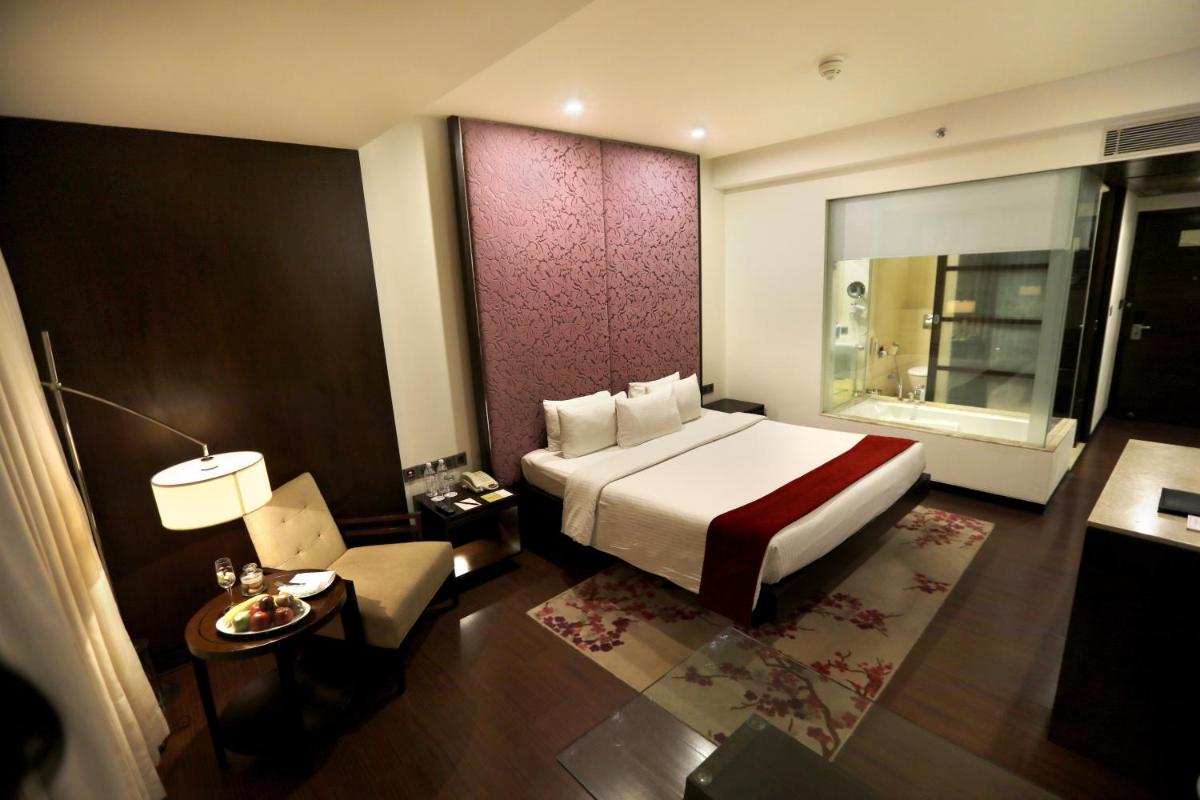 a bedroom with a bed and a table and a chair at Hotel Royal Orchid Jaipur, Tonk Road in Jaipur