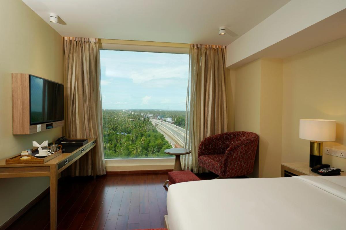 a hotel room with a bed and a desk and a window at O by Tamara, Trivandrum in Trivandrum