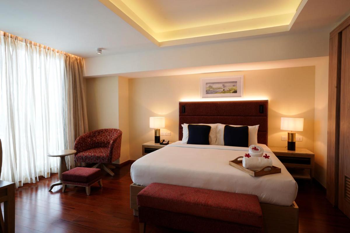 a hotel room with a large bed and a chair at O by Tamara, Trivandrum in Trivandrum