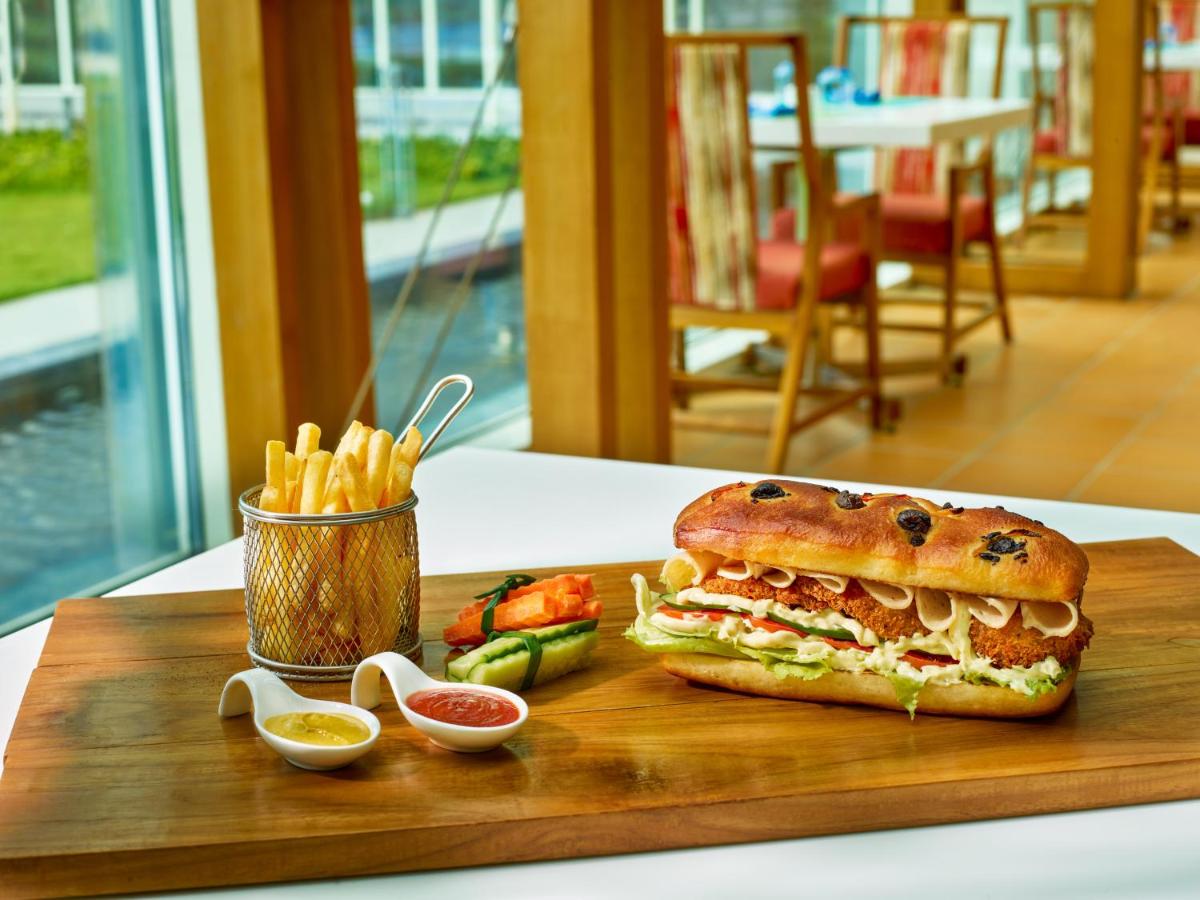 a sandwich and french fries on a wooden cutting board at O by Tamara, Trivandrum in Trivandrum