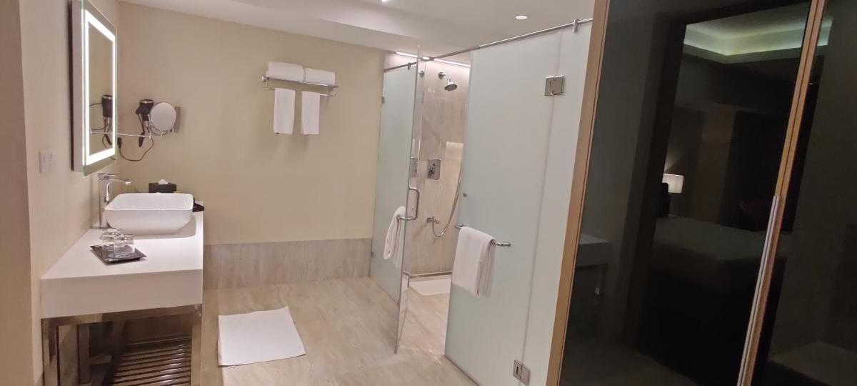 a white bathroom with a shower and a sink at O by Tamara, Trivandrum in Trivandrum
