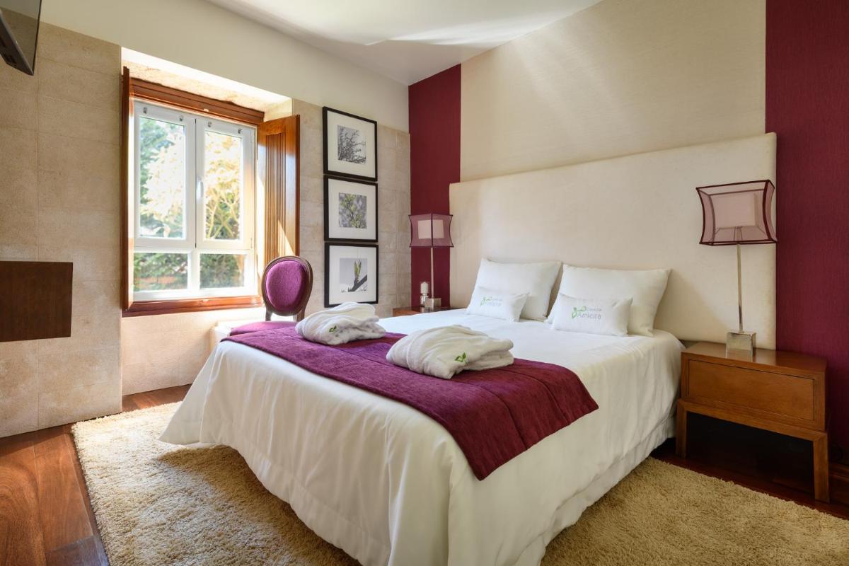 um quarto com uma grande cama branca e uma janela em Hotel de Charme Casa da Amieira em Amiães de Cima