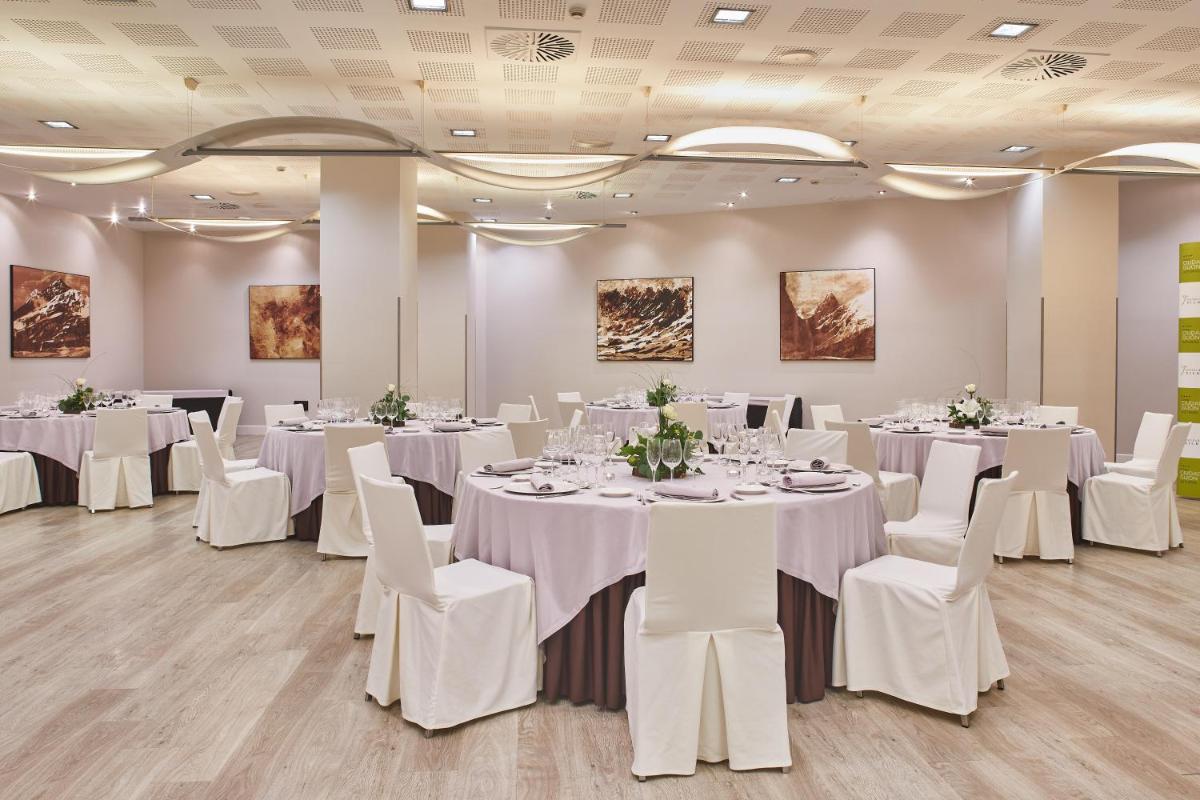 una sala de conferencias con mesas blancas y sillas blancas en Silken Ciudad Gijón, en Gijón