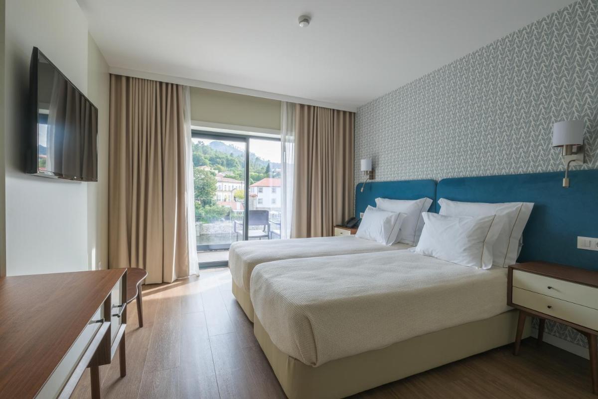 um quarto com uma cama grande com cabeceira azul em Hotel Vouga nas Termas de São Pedro do Sul