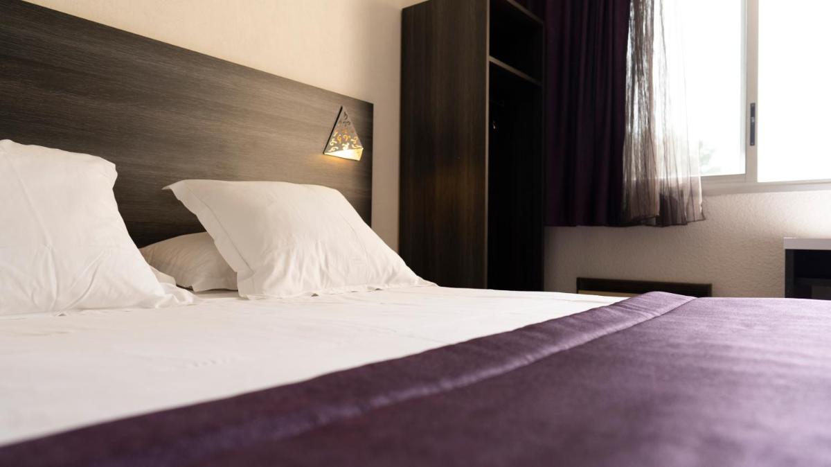 Un ou plusieurs lits dans un hébergement de l'établissement Logis Hotel Restaurant SPA Les Oliviers