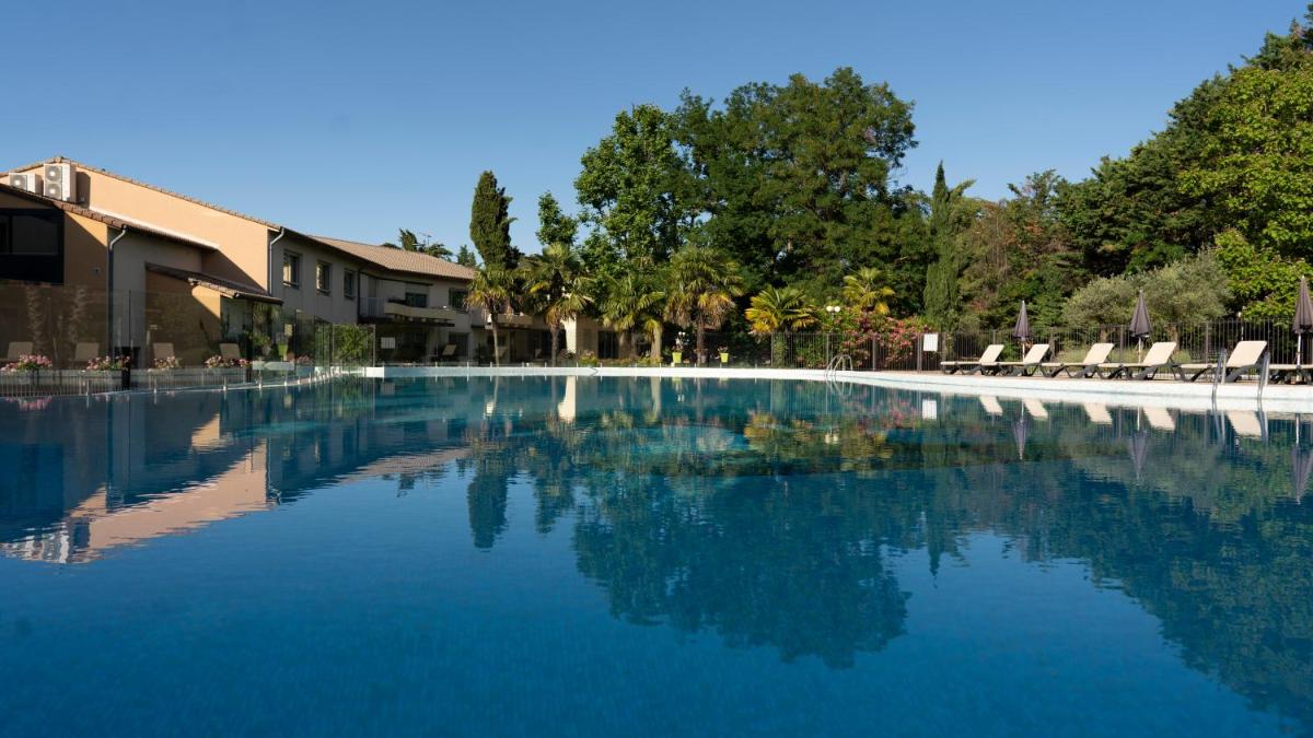 une piscine à l'eau bleue dans un complexe hôtelier dans l'établissement Logis Hotel Restaurant SPA Les Oliviers, à Loriol-sur-Drôme