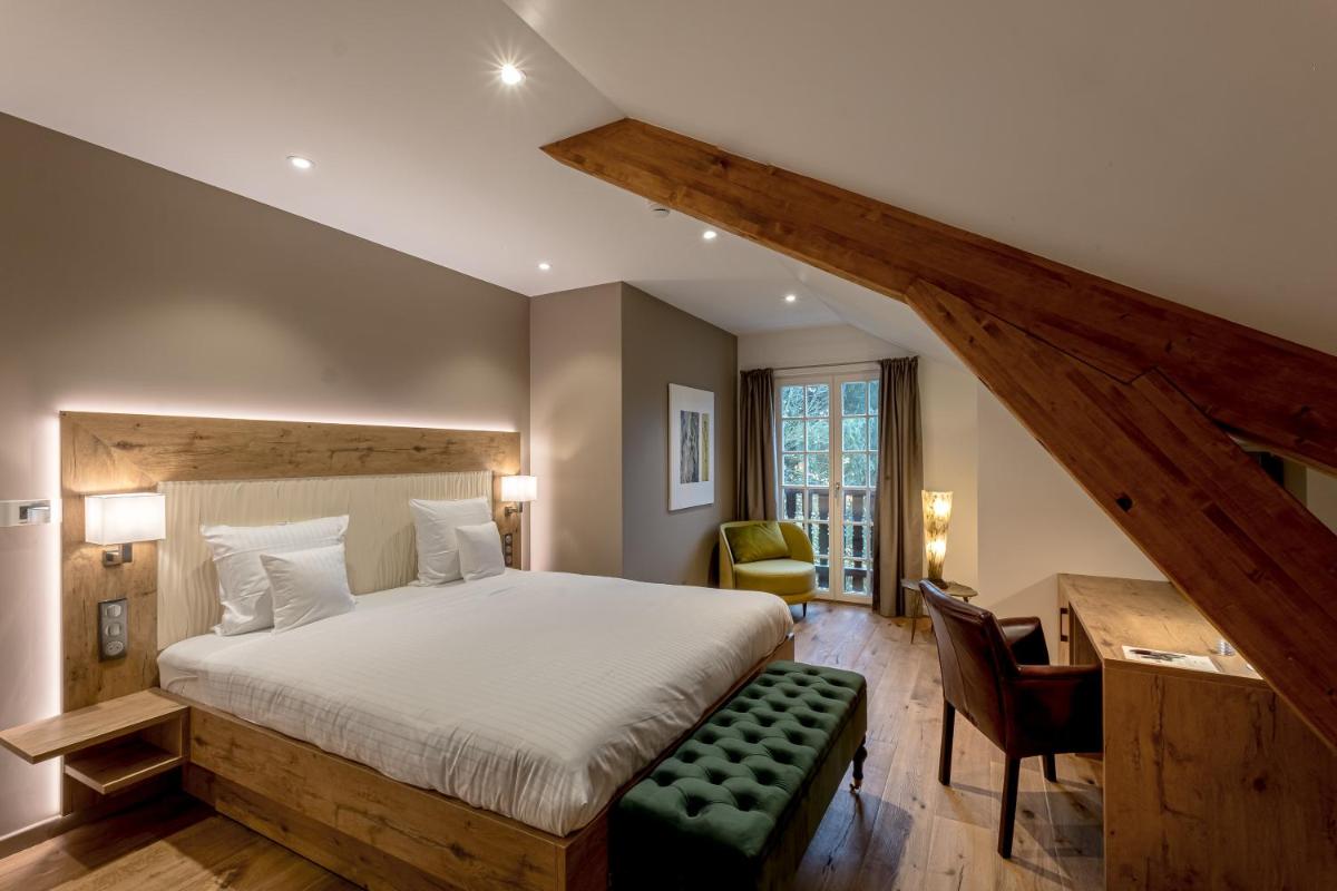 une chambre avec un grand lit avec un banc vert dans l'établissement Château de Pourtalès, à Strasbourg
