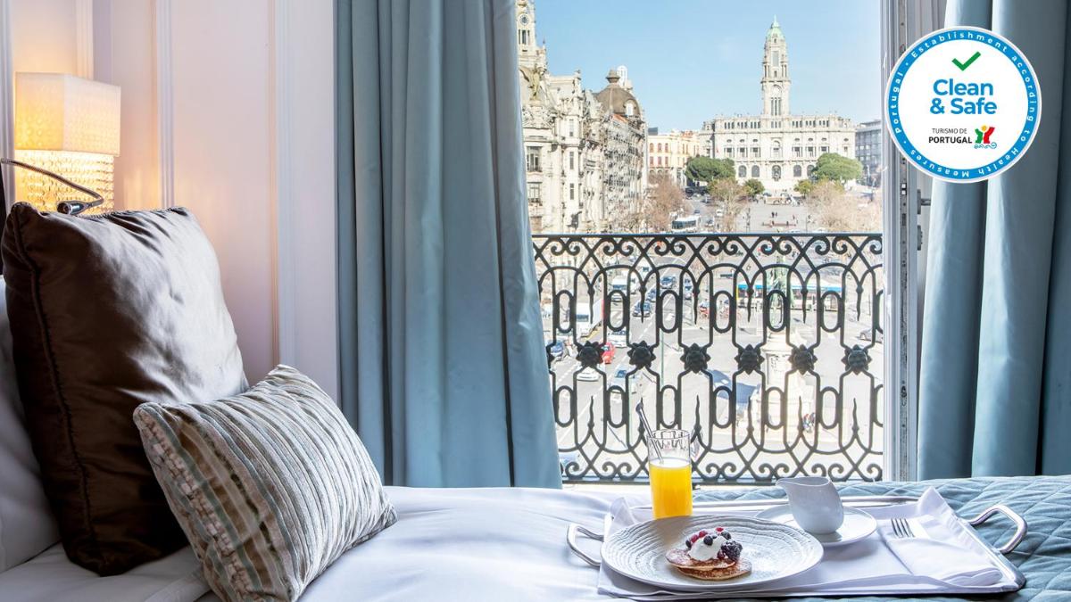 uma mesa com um prato de comida numa cama com uma janela em InterContinental Porto - Palacio das Cardosas by IHG no Porto mais 291 fotografias