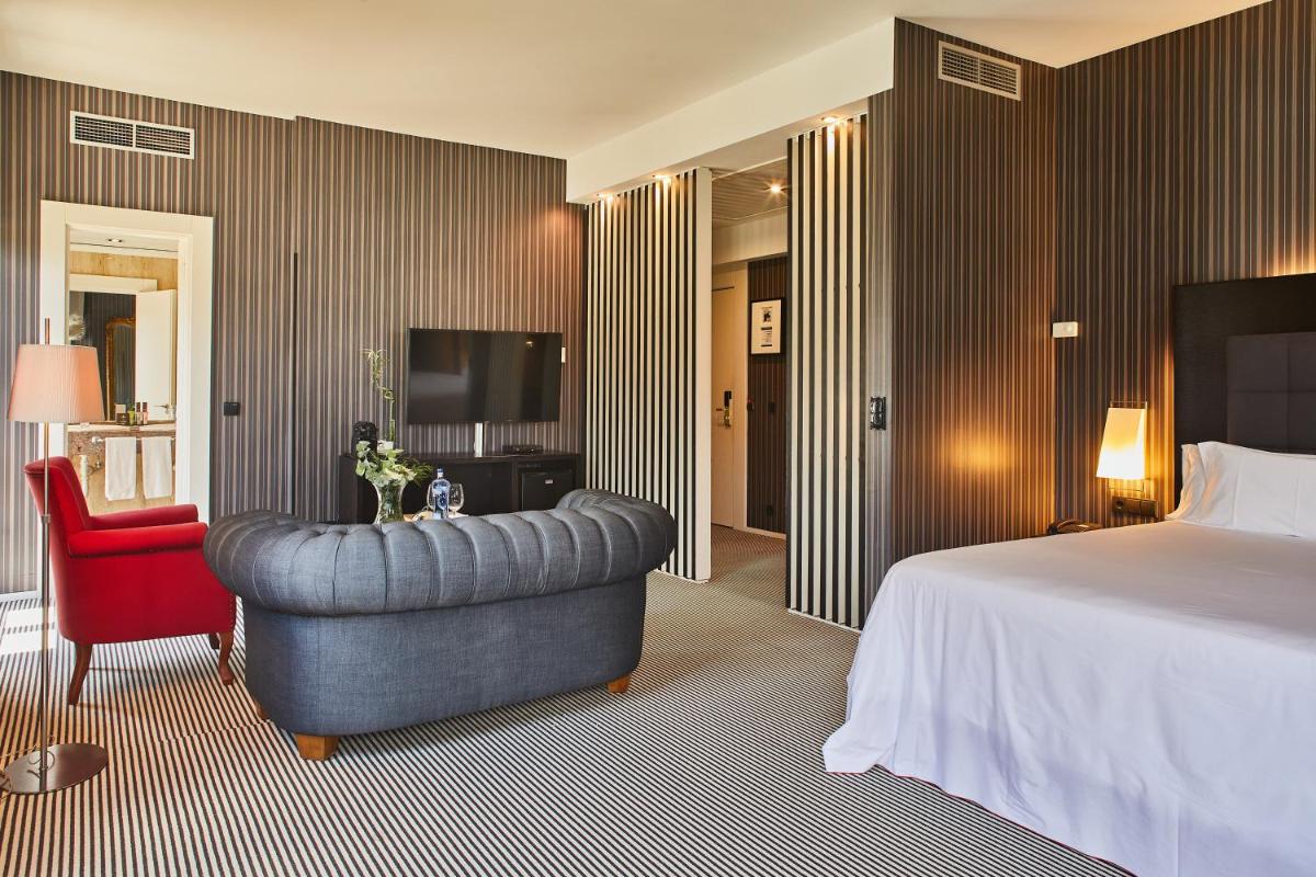 Una habitación de hotel con una cama, una silla y un televisor. en Silken Gran hotel Durango, en Durango