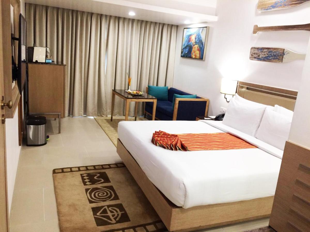 a hotel room with a large bed and a chair at Radisson Goa Candolim in Candolim