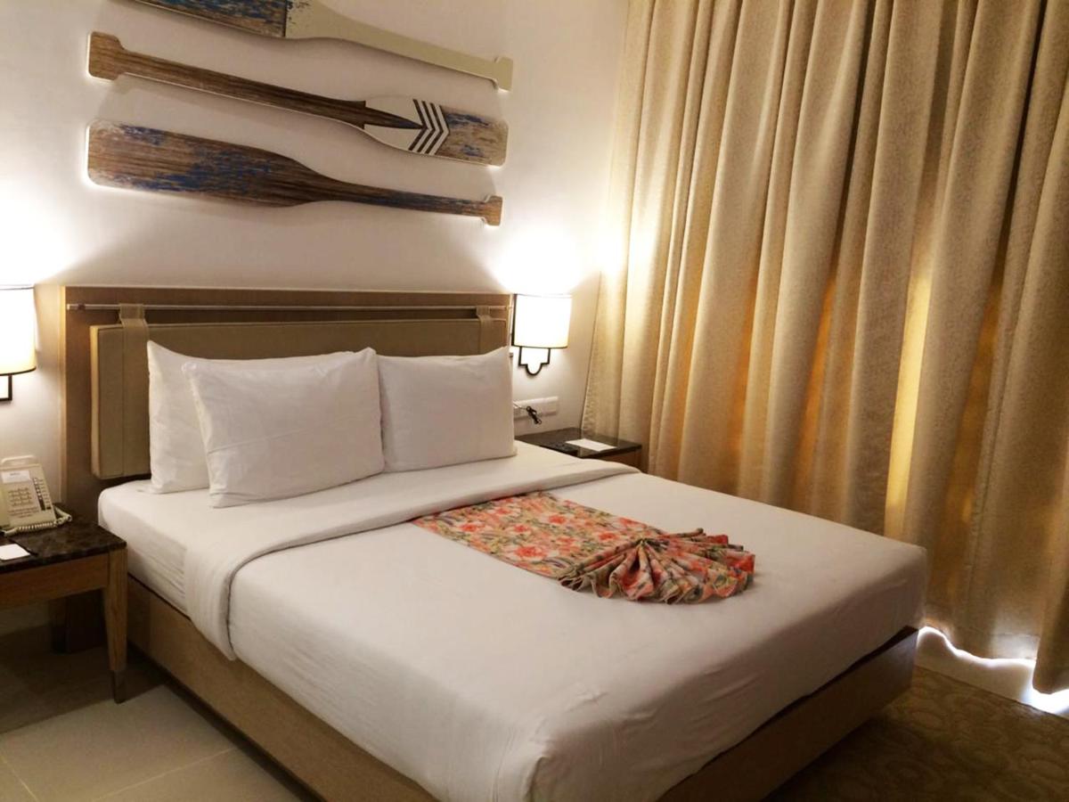 a hotel room with a white bed with a pillow at Radisson Goa Candolim in Candolim