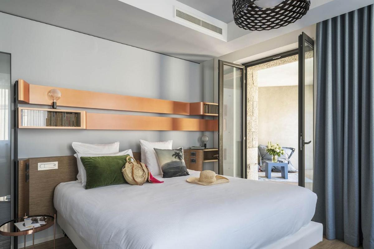une chambre avec un grand lit blanc et des oreillers verts dans l'établissement Golden Tulip Saint Malo– Le Grand Bé, à Saint-Malo