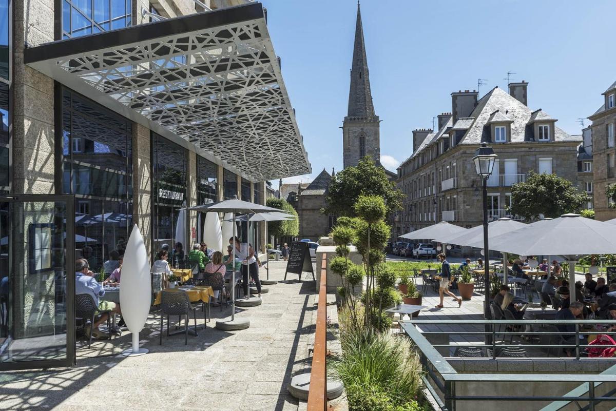 un groupe de personnes assises à des tables dans une rue de la ville dans l'établissement Golden Tulip Saint Malo– Le Grand Bé, à Saint-Malo