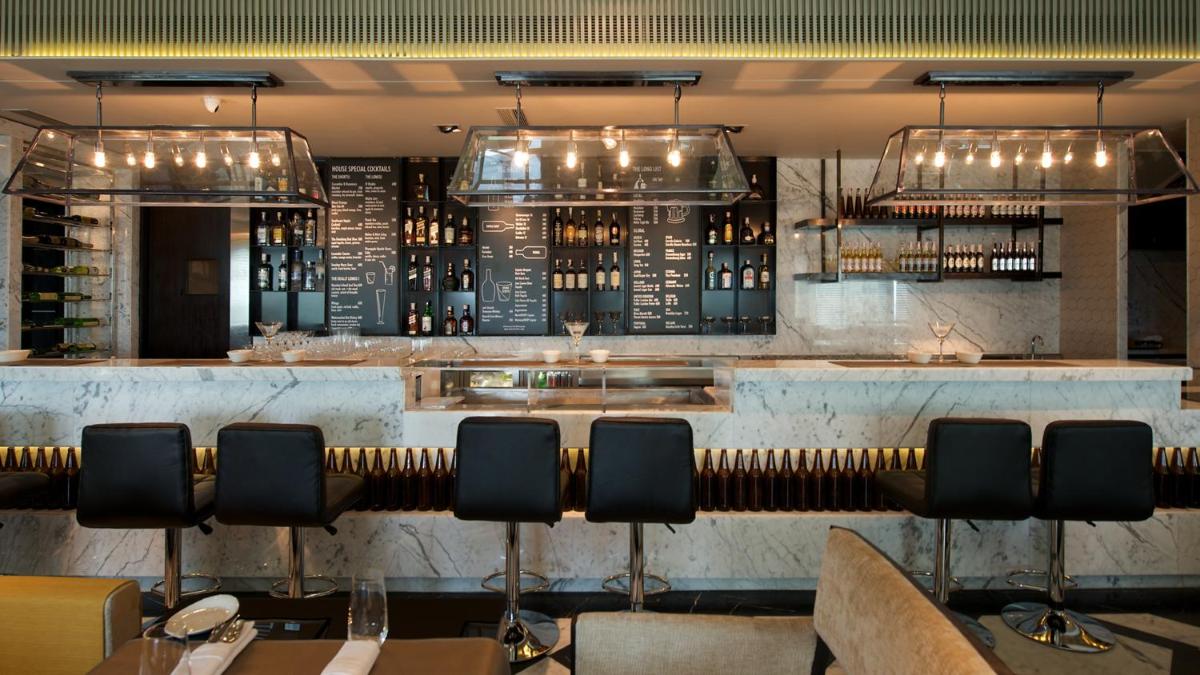a restaurant with a bar with chairs and wine bottles at InterContinental Marine Drive Mumbai by IHG in Mumbai