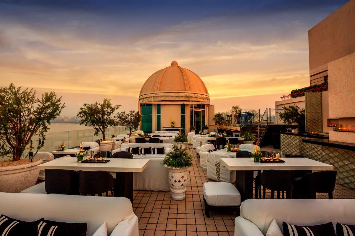 a restaurant with white tables and chairs and a building at InterContinental Marine Drive Mumbai by IHG in Mumbai