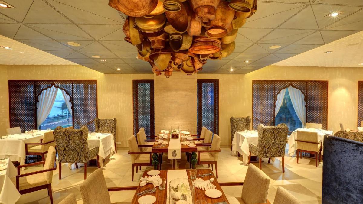 a restaurant with tables and chairs and a chandelier at InterContinental Marine Drive Mumbai by IHG in Mumbai