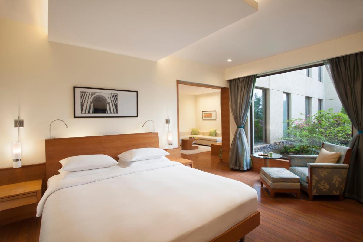 a bedroom with a large bed and a large window at Hyatt Pune in Pune