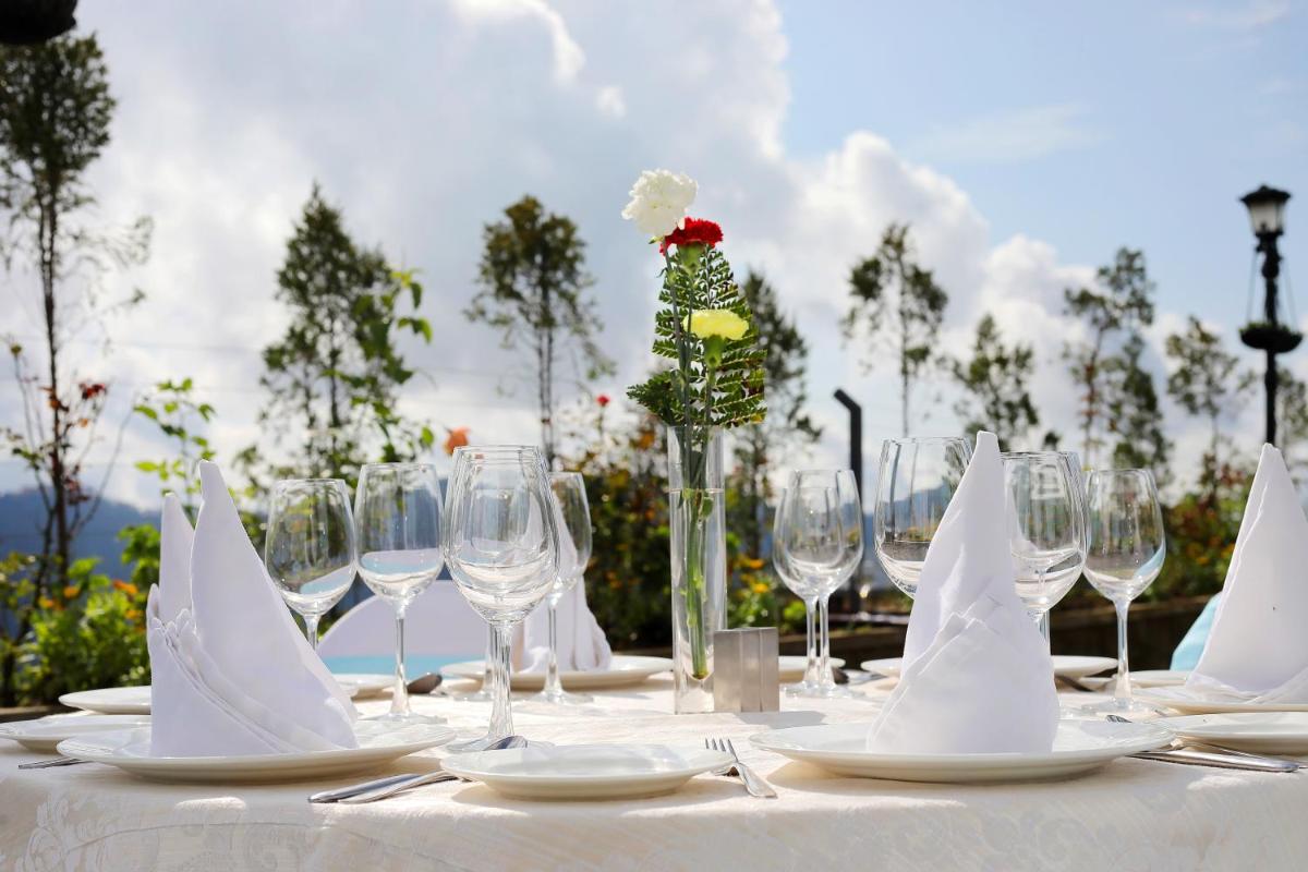 a white table with wine glasses and a flower in a vase at Welcomhotel by ITC Hotels, Shimla in Shimla