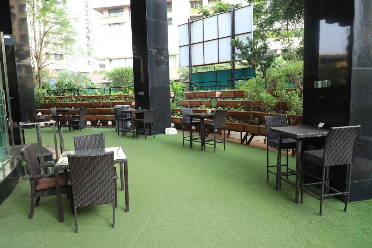 a restaurant with tables and chairs on a green floor at Sofitel Mumbai BKC in Mumbai