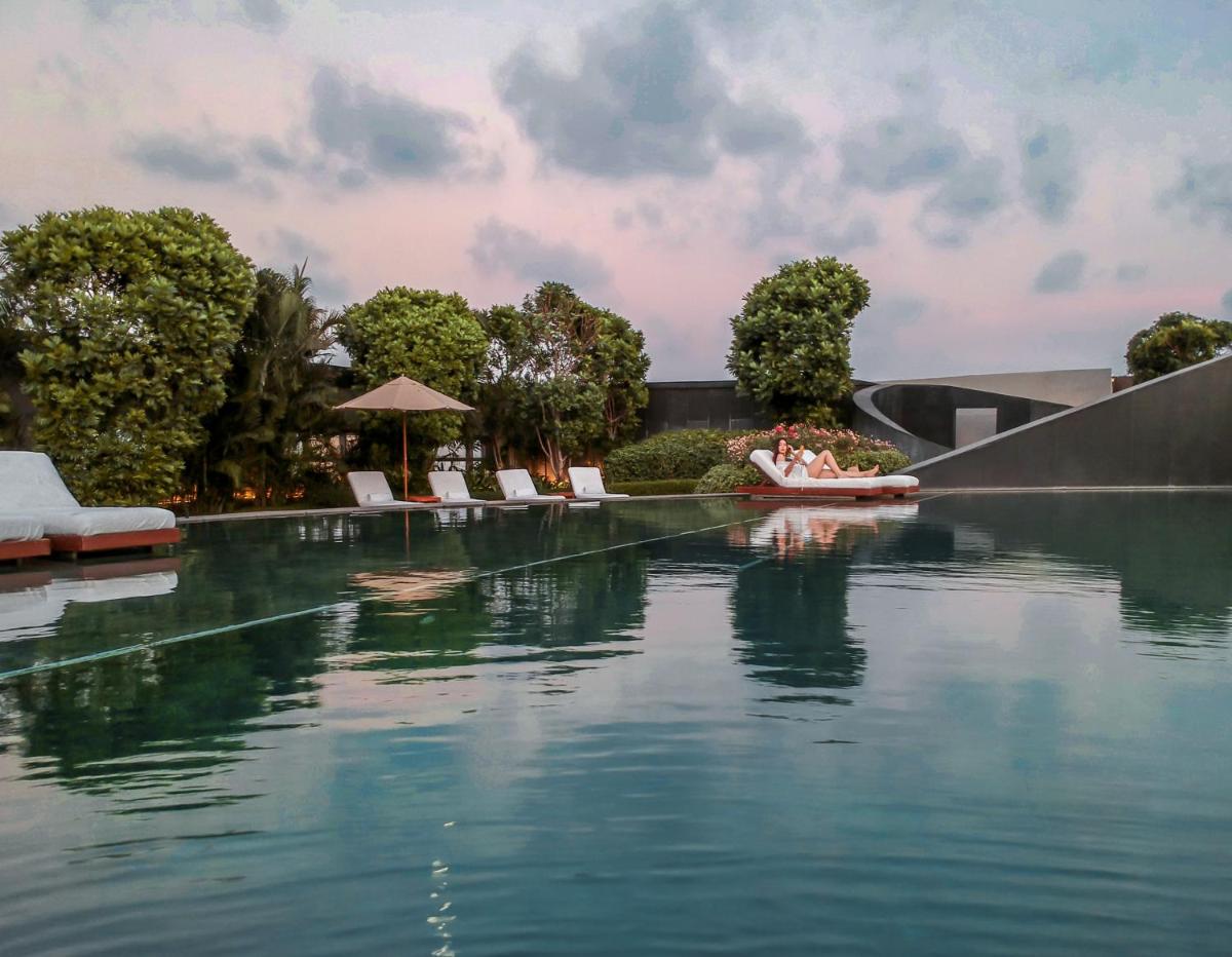 a pool of water with chairs and trees and a building at Park Hyatt Chennai in Chennai