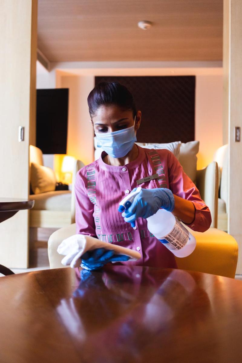 a woman sitting at a table wearing a mask and gloves at Park Hyatt Chennai in Chennai