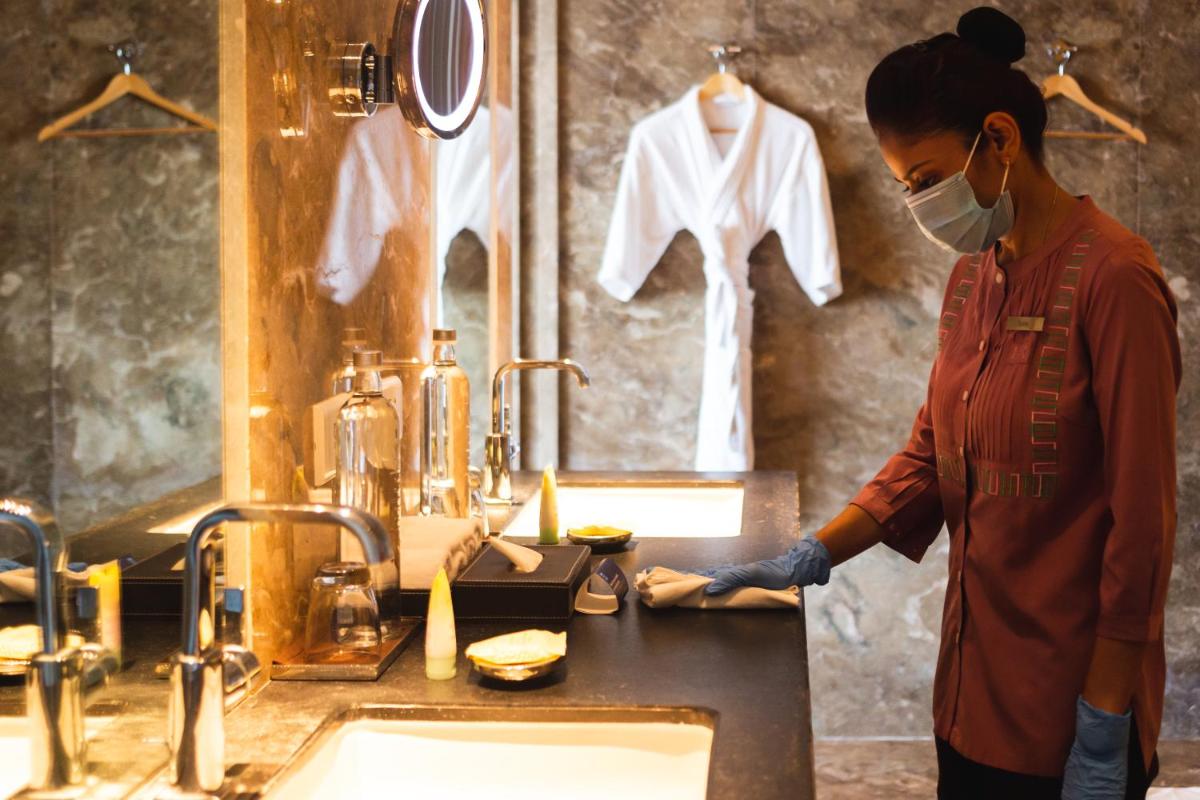 a woman in a mask standing in a bathroom with a sink at Park Hyatt Chennai in Chennai