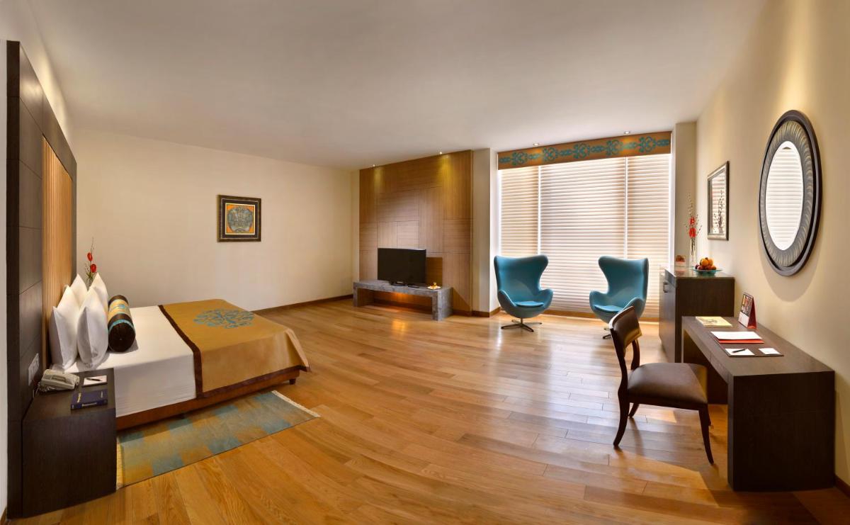 a room with a bed and two chairs and a desk at The Lalit Great Eastern Kolkata in Kolkata a room with a bed and two chairs and a desk at The Lalit Great Eastern Kolkata in Kolkata