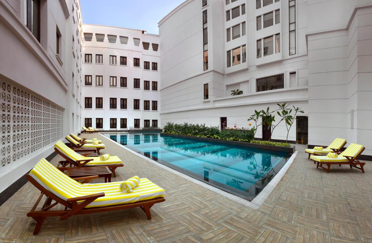 a hotel with a pool and chairs and a building at The Lalit Great Eastern Kolkata in Kolkata a hotel with a pool and chairs and a building at The Lalit Great Eastern Kolkata in Kolkata