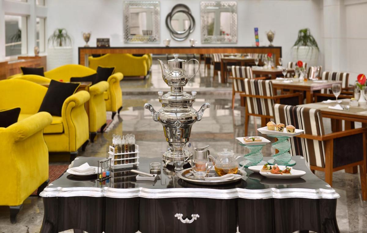 a dining room with yellow chairs and a table with food at The Lalit Great Eastern Kolkata in Kolkata a dining room with yellow chairs and a table with food at The Lalit Great Eastern Kolkata in Kolkata